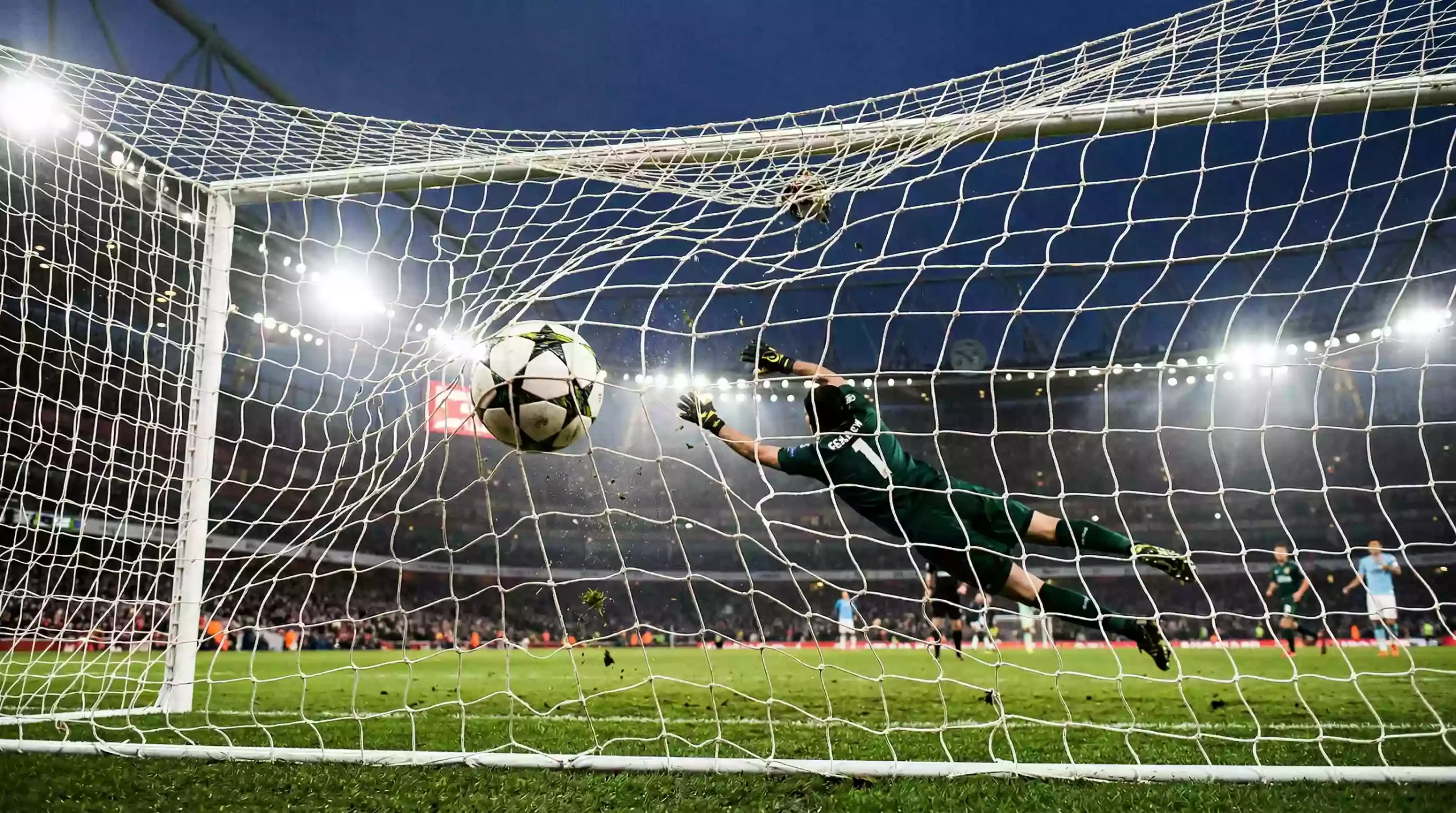 Voetbal vliegt in het doel langs de doelman tijdens een avondwedstrijd